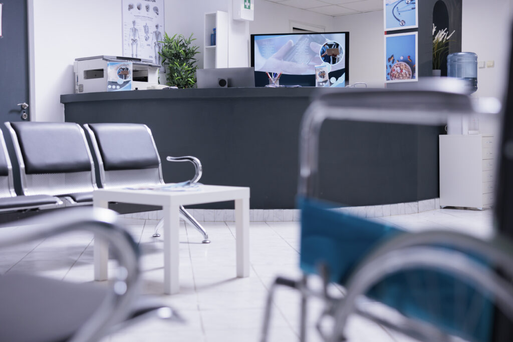 Front desk of medical office reception zone with technological devices, office supplies and medical utilities. Patient reception area with no staff members attending to anyone. Nobody in clinic lobby.